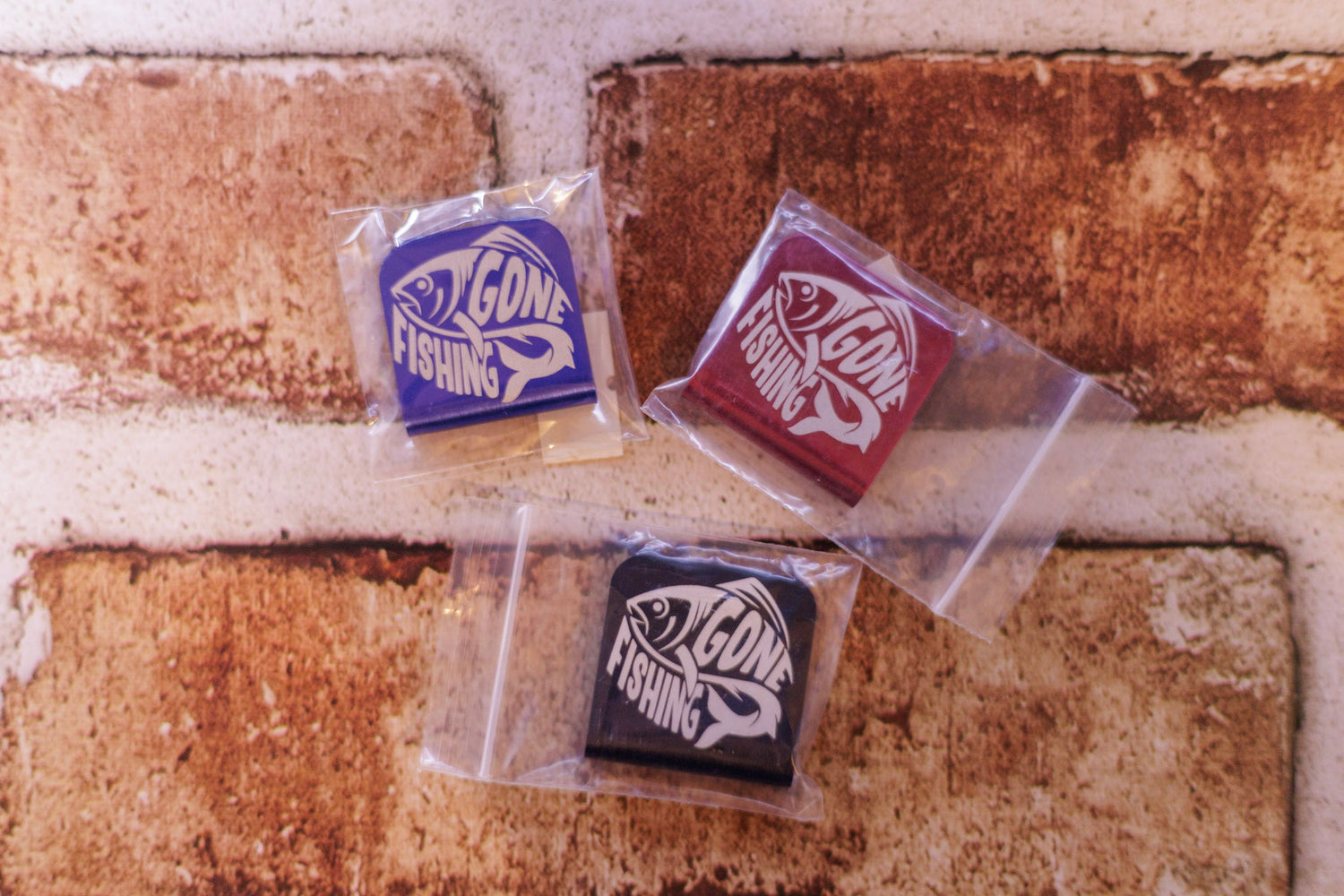 Three fishing lure packages with visible branding on a brick background